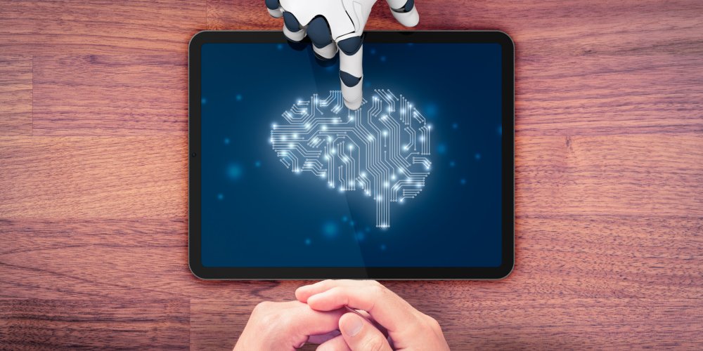 Artificial intelligence concept with robotic hand pointing at br Artificial intelligence (AI) concept with robotic hand pointing at tablet with brain in PCB design and hands of business person, top view flatlay composition.